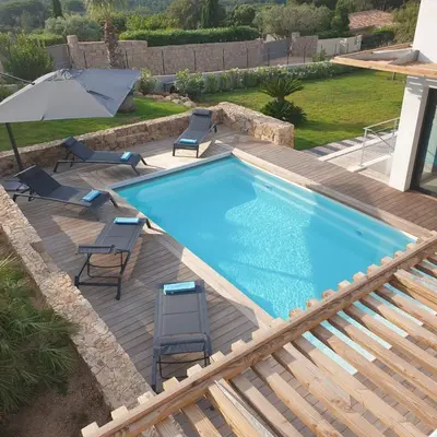 a swimming pool with chairs and an umbrella at Villa Maria 12 pers piscine chauffée 5 min plage en voiture in Sainte-Lucie de Porto-Vecchio