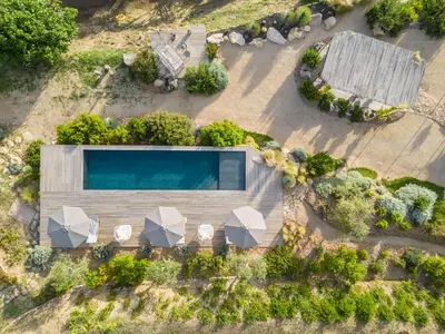 an overhead view of a swimming pool with umbrellas at Terre de Maquis, maison d'hôtes vue mer Corse in Sari-dʼOrcino
