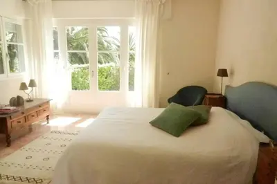 a bedroom with a large bed with a large window at Grande maison au cadre verdoyant au centre village in Cargèse