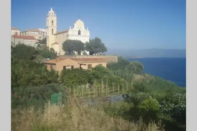 a building on top of a hill next to the ocean at Grande maison au cadre verdoyant au centre village in Cargèse