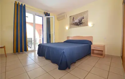 a bedroom with a blue bed and a window at Cozy Apartment In Propriano With Wifi in Propriano