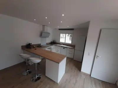 a large white kitchen with a counter and stools at Villa_Culomba ALATA -T2 4 couchages in Alata