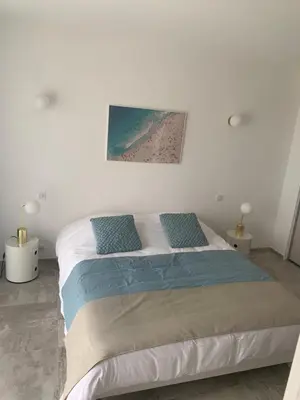 a white bedroom with a bed with blue pillows at LES VILLAS DU DOMAINE NAPOLEON CORSICA vue mer et piscine in Pietrosella