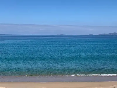 a large body of water with a beach and the ocean at LES VILLAS DU DOMAINE NAPOLEON CORSICA vue mer et piscine in Pietrosella