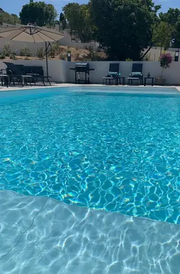 a pool of blue water with tables and chairs at LES VILLAS DU DOMAINE NAPOLEON CORSICA vue mer et piscine in Pietrosella