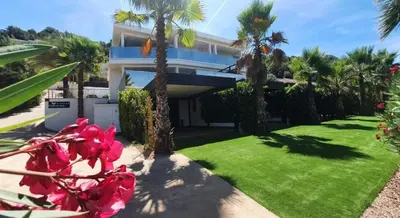 a house with palm trees and red flowers in the yard at Les Jardins de la Palmeraie - Sublime vue sur la baie dAjaccio in Porticcio