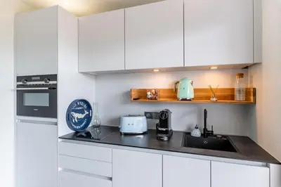 a kitchen with white cabinets and a black counter top at Les Jardins de la Palmeraie - Sublime vue sur la baie dAjaccio in Porticcio