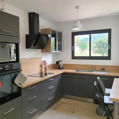 a kitchen with gray cabinets and a sink and a window at Villa Leku Lucia 8 pers piscine chauffée 15 min plage en voiture in Sainte-Lucie de Porto-Vecchio