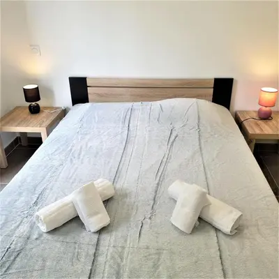a bed with two towels on it with two tables at Villa Leku Lucia 8 pers piscine chauffée 15 min plage en voiture in Sainte-Lucie de Porto-Vecchio