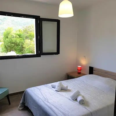 a bedroom with a bed with two towels on it at Villa Leku Lucia 8 pers piscine chauffée 15 min plage en voiture in Sainte-Lucie de Porto-Vecchio