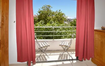 a balcony with two chairs and red curtains at Gorgeous Apartment In Propriano in Propriano