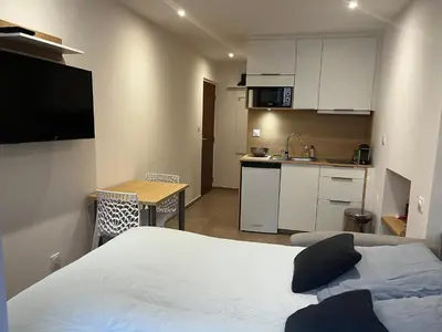 a bedroom with a bed and a small kitchen at Charmant studio au cœur de la rue Fesch d'Ajaccio in Ajaccio