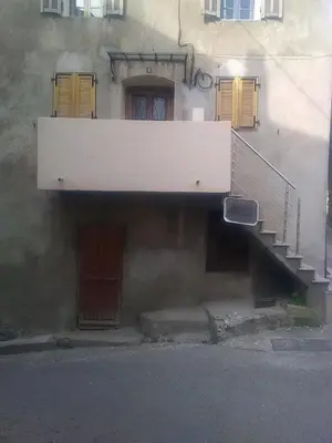 a building with a staircase and a building with yellow doors at Charmant petit studio proche départ GR20 in Calenzana
