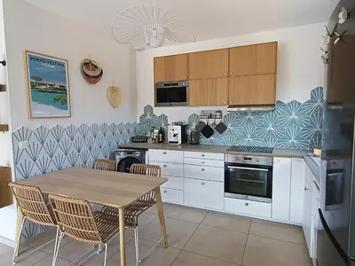 a kitchen with white cabinets and a table and chairs at Villa intimiste avec piscine privée chauffée in Lecci