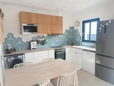 a kitchen with a table and a refrigerator at Villa intimiste avec piscine privée chauffée in Lecci
