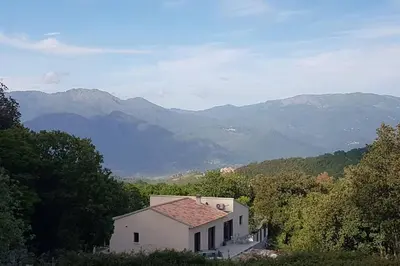 a small white house with mountains in the background at VILLA Adrien , maison de charme. in Casanova