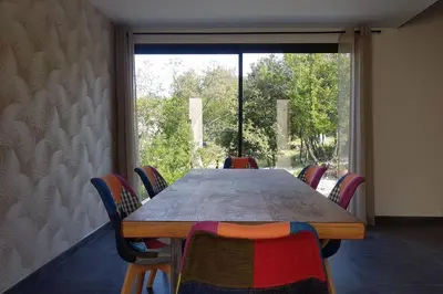 a table and chairs in a room with a large window at VILLA Adrien , maison de charme. in Casanova