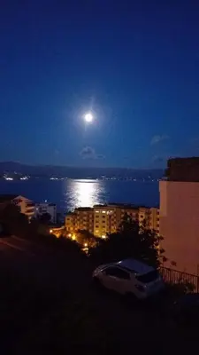 a full moon over the water at night at AJACCIO VUE MER ET MONTAGNES JACUZZI 300M PLAGEs in Ajaccio