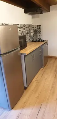 a kitchen with a refrigerator and a wooden floor at Appartement de charme vieille ville in Corte