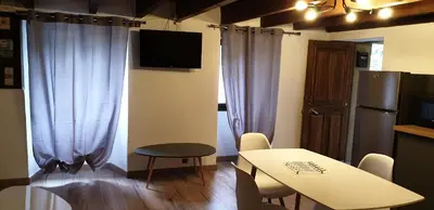 a living room with a table and a kitchen with a tv at Appartement de charme vieille ville in Corte