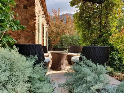 a patio with wicker chairs and tables in a garden at Domaine Codaleone in Serriera