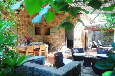 a patio with a table and chairs and a stone wall at Domaine Codaleone in Serriera