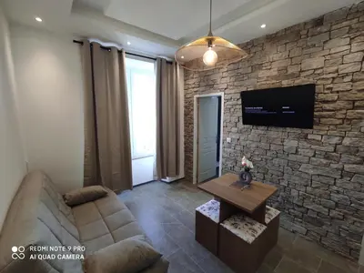 a living room with a couch and a tv on a brick wall at BRILOC AJACCIO centre ville in Ajaccio