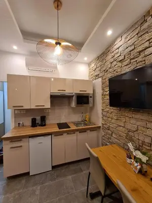 a kitchen with white cabinets and a stone wall at BRILOC AJACCIO centre ville in Ajaccio