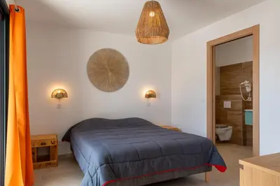 a bedroom with a bed with a blue comforter at Les Villas de la Résidence U Veniqui in Favone