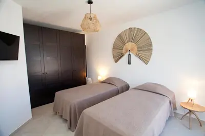 a bedroom with two beds and a fan on the wall at Les Villas de la Résidence U Veniqui in Favone