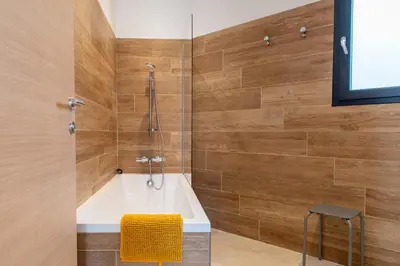 a bathroom with a tub and a chair in it at Les Villas de la Résidence U Veniqui in Favone