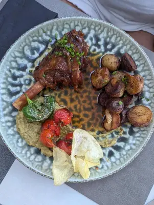 a plate of food with meat and potatoes on a table at Les Villas de la Résidence U Veniqui in Favone