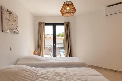 a white bedroom with a bed and a window at Les Villas de la Résidence U Veniqui in Favone