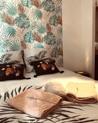 a bed with pillows and towels on it with a wall at chez LULU appartement neuf au coeur de cozzano in Cozzano