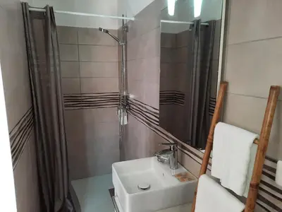 a bathroom with a sink and a shower and a mirror at Les Jardins De Santa Giulia - Charmante chambre dhte in Porto-Vecchio