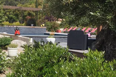 a person sitting on a bench next to a swimming pool at Les Jardins De Santa Giulia - Charmante chambre dhte in Porto-Vecchio
