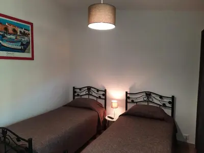 a bedroom with two beds and a light on the wall at Les Jardins De Santa Giulia - Charmante chambre dhte in Porto-Vecchio