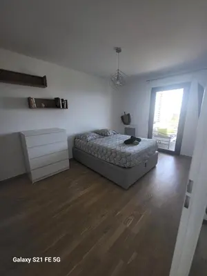 a white bedroom with a bed and a wooden floor at T2 VUE MER - ENTREE DE VILLE in Ajaccio