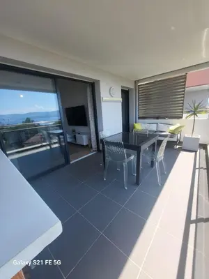 a living room with a table and chairs and a television at T2 VUE MER - ENTREE DE VILLE in Ajaccio