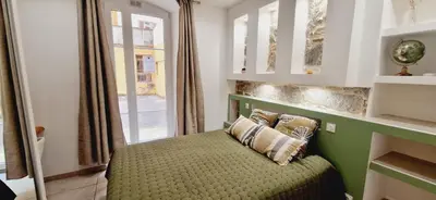 a bedroom with a green bed with a window at Appartement plein de charme - Ajaccio hyper centre in Ajaccio