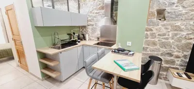 a small kitchen with a wooden table and a counter at Appartement plein de charme - Ajaccio hyper centre in Ajaccio