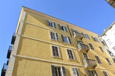 a yellow building with white windows on a street at Appartement plein de charme - Ajaccio hyper centre in Ajaccio