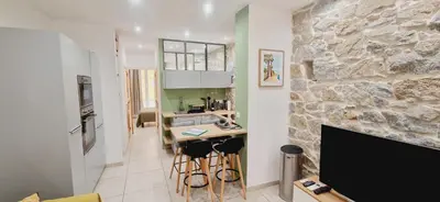a living room with a stone wall and a kitchen at Appartement plein de charme - Ajaccio hyper centre in Ajaccio