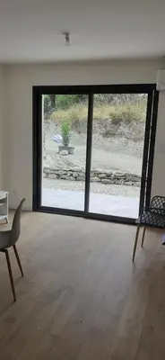 a living room with a large window and a table and a chair at Casa Prunelli in Omessa