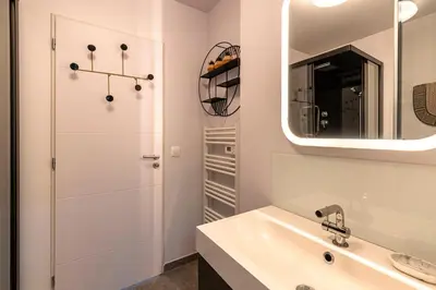 a white bathroom with a sink and a mirror at Splendide appartement T3 piscine et vue mer in Grosseto-Prugna