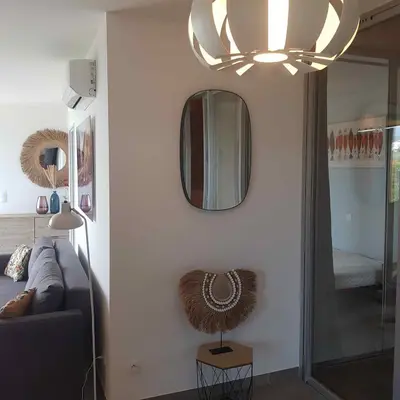 a living room with a couch and a mirror at Splendide appartement T3 piscine et vue mer in Grosseto-Prugna