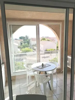 a balcony with a table and chairs in front of a window at Studio 4 personnes bord de mer avec piscine wifi in Cervione