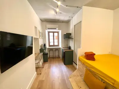 a small room with a yellow bed and a kitchen at Studio d'architecte centre historique in Ajaccio