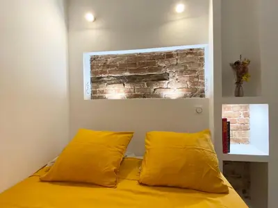 a bedroom with two yellow pillows and a brick wall at Studio d'architecte centre historique in Ajaccio