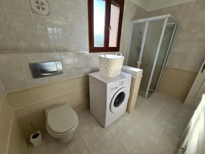a bathroom with a washing machine and a toilet at Les Terrasses de Sari in Sari Solenzara